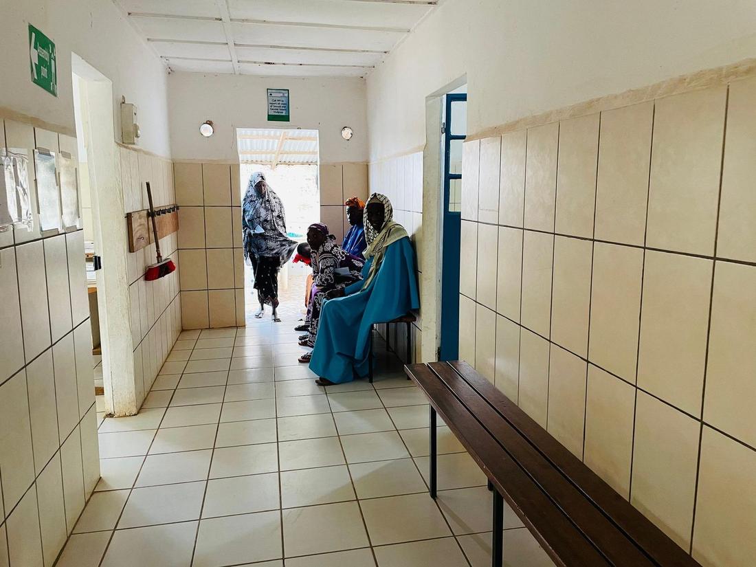 Patientinnen warten im gefliesten Flur des Rose Health Center.